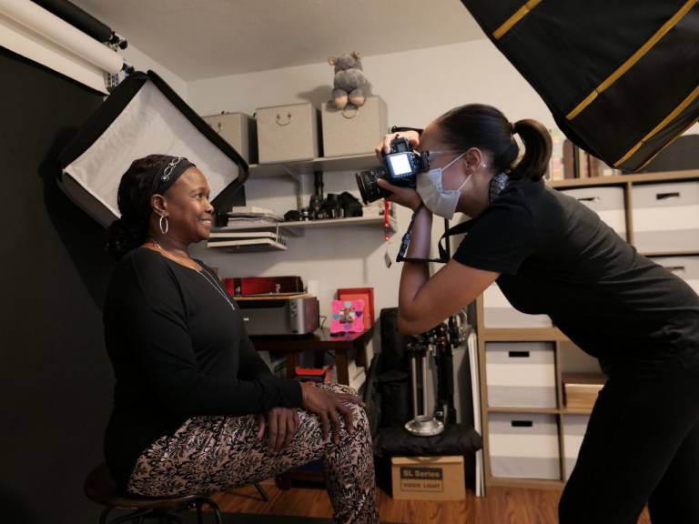Heather Avant raises her camera to photograph a woman.