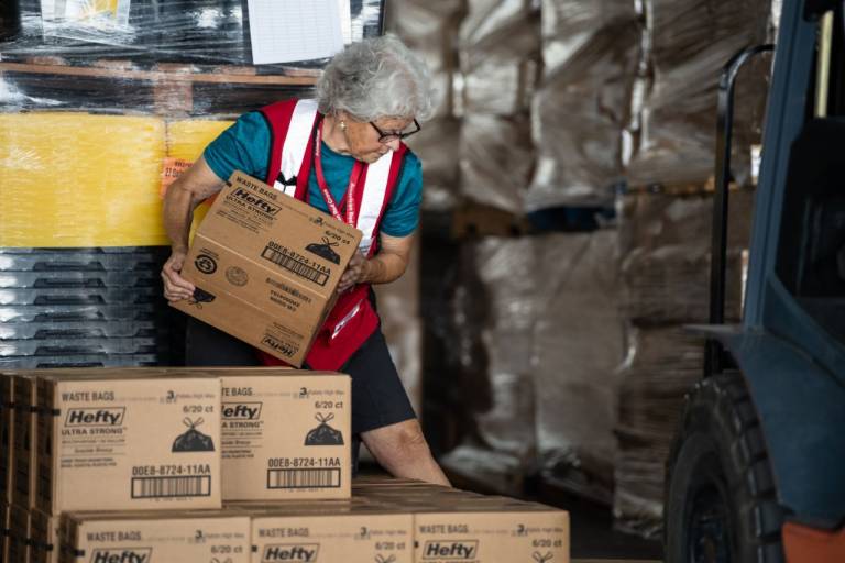 Woman in Red Cross vest moves boxes