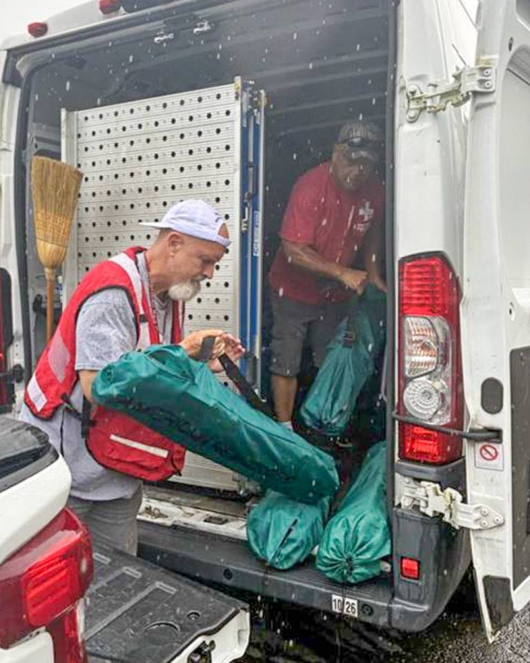 two men in Red Cross vests unload relief supplies