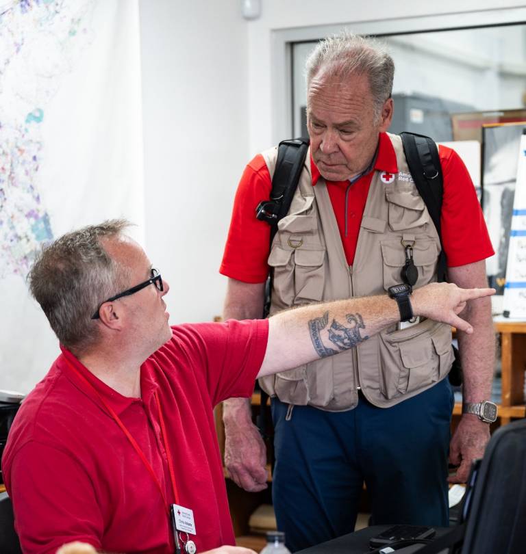 Two men, one sitting, one standing, have a discussion