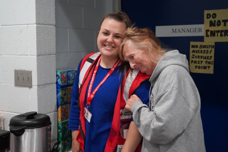 Woman in Red Cross vest stands with woman in gray sweatshirt