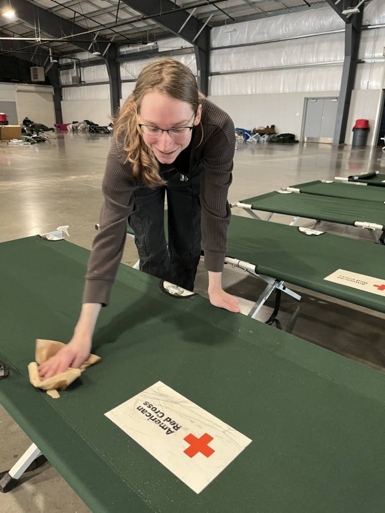 man wipes down cots in a shelter