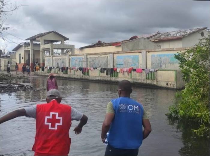 people in Red Cross vests clean up debris in standing water.