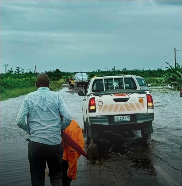Man stands next to a small truck near floodwaters.