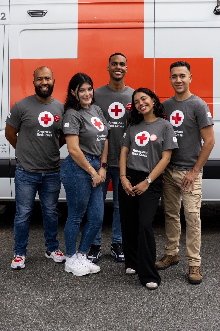 a group of young adults standing in front of an emergency response vehicle