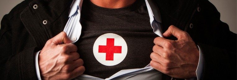 A man in a jacket who is prentending to be a hero by pulling it apart to expose a Red Cross t shirt 