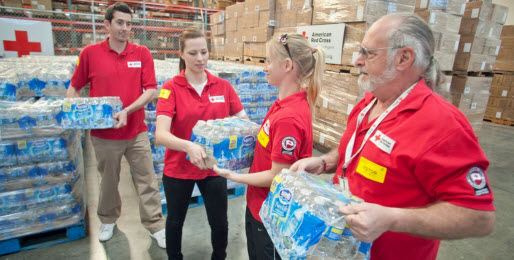 Four American Red Cross volunteers holding cases of bottled water.