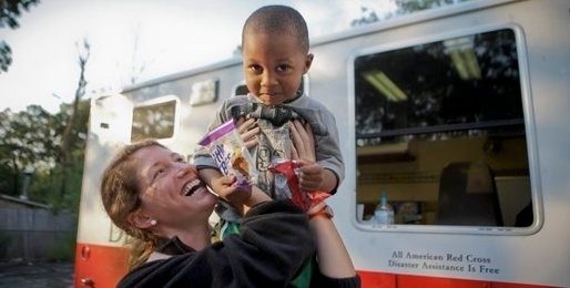 Woman smiling holding a child above her head.