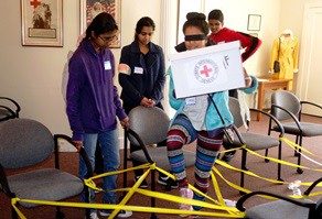 Students playing Raid Cross inside a room with chairs and caution tape.