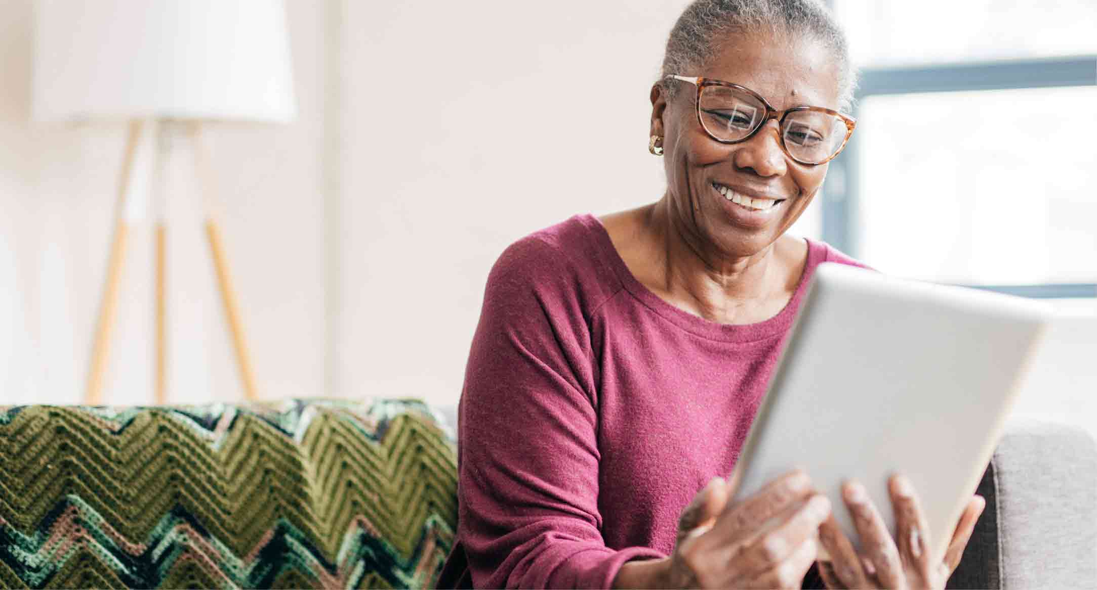 Image of woman smiling while looking at her tablet