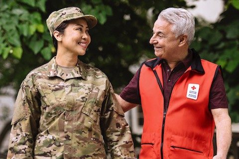 Red Cross volunteer walking with female military member
