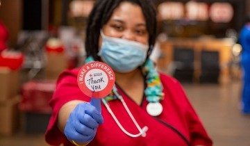 Red Cross phlebotomist holding sticker that says thank you