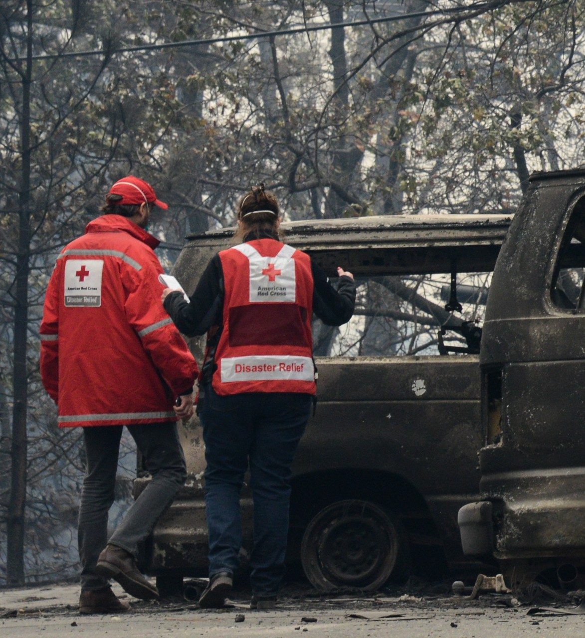 red cross volunteers look over fire damaged vehicles