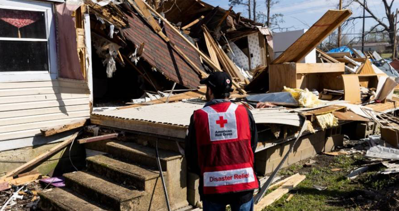 un voluntario observa los daños causados por el viento en un edificio