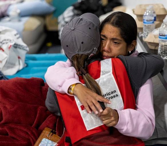 A Red Cross volunteer embraces a woman in a shelter