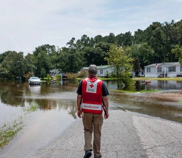 Un voluntario de la Cruz Roja Americana se encuentra con vistas a un barrio inundado.
