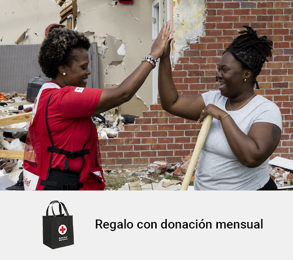 Un voluntario de la Cruz Roja choca los cinco con una mujer sonriente mientras trabajan limpiando una casa destruida por un desastre. El texto que aparece a continuación dice "Regalo gratuito con donación mensual" junto a una imagen de una bolsa de mano.