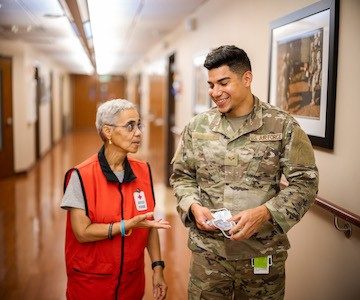 Red Cross volunteer and man in military uniform walking down a hallway