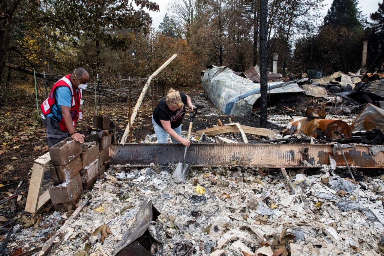 September 19, 2020. Gates, Oregon.American Red Cross volunteer Eric Carmichael helps Laura who has come to look through the remains of her home that burned to the ground in the Oregon wildfires, in Gates, OR on Saturday September 19, 2020. Sifters are a simple tool but mean so much to people who are in search of anything that is salvageable from their home.Photo by Scott Dalton/American Red Cross