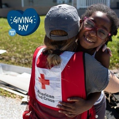 A Red Cross volunteer hugs a child who has experienced a disaster