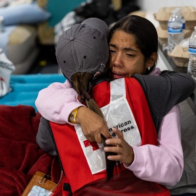 A Red Cross volunteer comforts a woman in an emergency shelter