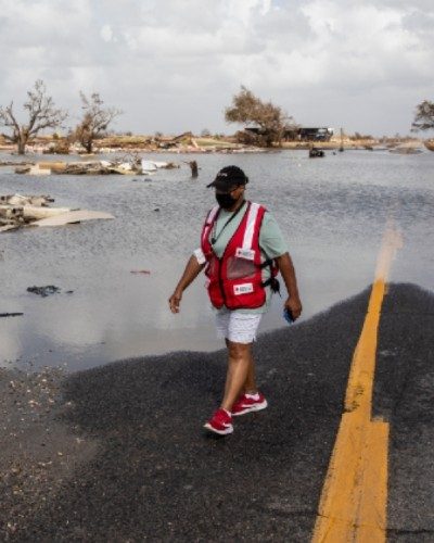 A Red Cross volunteer walking through a disaster site.