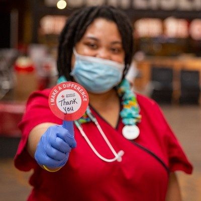 Red Cross phlebotomist holding sticker that says thank you