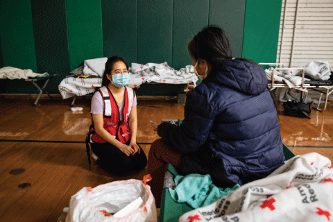 Red Cross volunteer speaking with woman in shelter