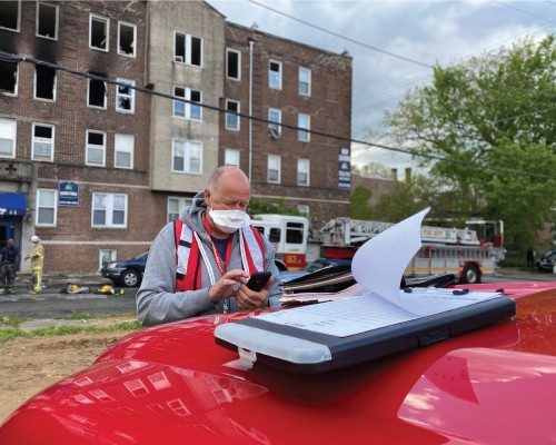 red cross volunteer standing next to a car preparing documents to provide financial assistance to victims of ahome fire 