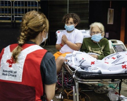 red cross worker shakes hand of military man