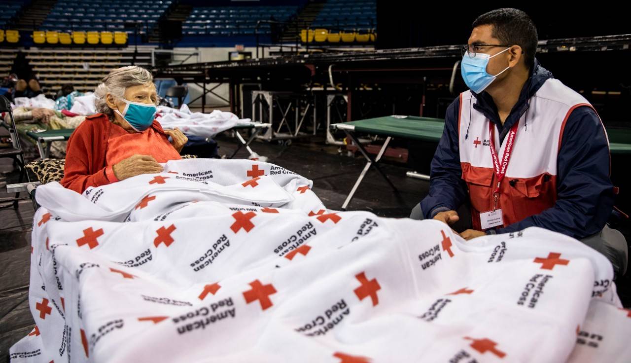 August 30, 2021. Baton Rouge, Louisiana. Michael Butcher of Vermont, a volunteer at a Red Cross evacuation center in Baton Rouge, talks with resident Ethel Savoie of Central LA on August 30, 2021. This is Michael s fourth Red Cross deployment in the past year. Since yesterday, he s been at the center helping to assemble cots and the feeding station, greeting residents and helping them to get acclimated as they hunkered down for Hurricane Ida to pass last night.  We appreciate what you all are doing,  said Ethel about the work of the Red Cross.  You do a beautiful job.  Photo by Scott Dalton/American Red Cross