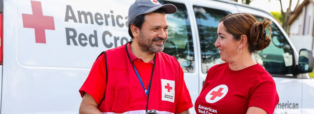 May 5, 2018. Smoke alarm installations at a Sound the Alarm event.Miami, Florida..Pictured: American Red Cross volunteer Xavier Placencia (left) and an unidentified Red Cross volunteer.American Red Cross volunteer Xavier Placencia and another volunteer discuss plans for going door-to-door in the Little Havana neighborhood of Miami, Florida during an event called "Sound the Alarm." Teams of Red Cross volunteers spent the day installing free smoke alarms in private homes. Similar events were held across the country to install smoke alarms in as many homes as possible, and to educate families about how to prevent, and escape from, a home fire. Photo by James McEntee for the American Red Cross.