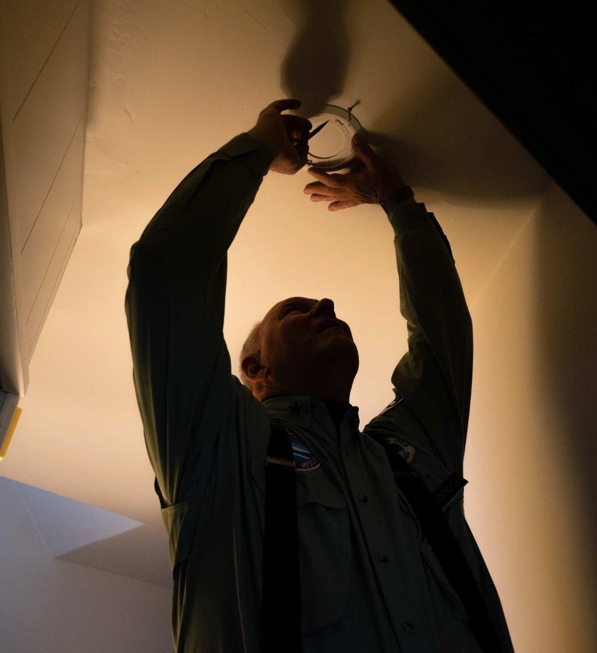 A man installs a smoke alarm