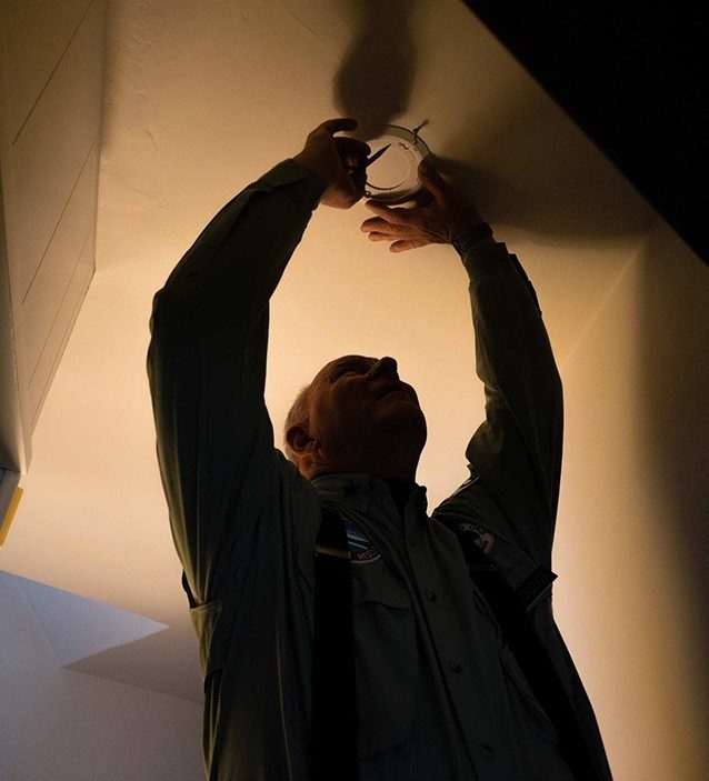 Man installing smoke alarm on ceiling