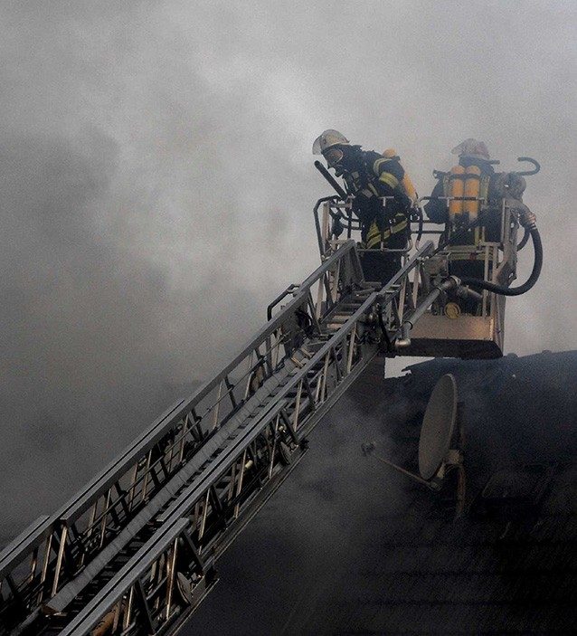 Firefighters on ladder fighting a fire