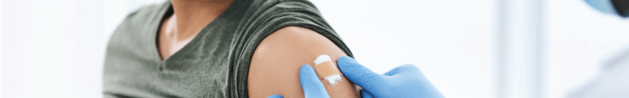 Clinician placing band aid over injection site on man's arm