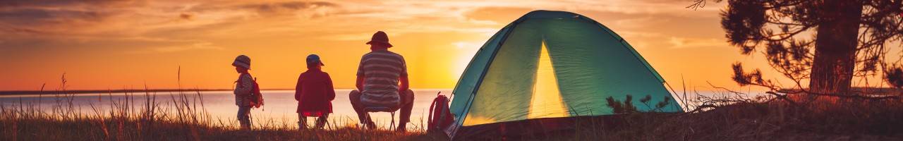 Family watching a sunset outside their tent