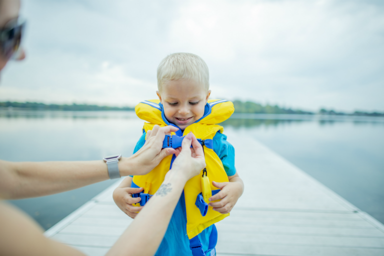 Parent checks young boy's life jacket buckles