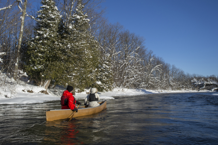 Couple canoeing together during the winter wearing life jackets