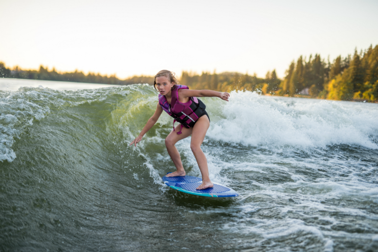Young girl wearing life jacket while surfing