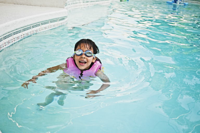Young girl in pool with lfe jacket on