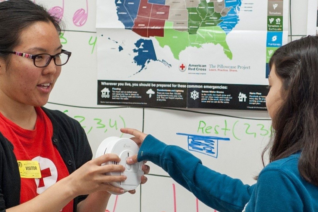 Red Cross Volunteer Helping Child With Smoke Alarm