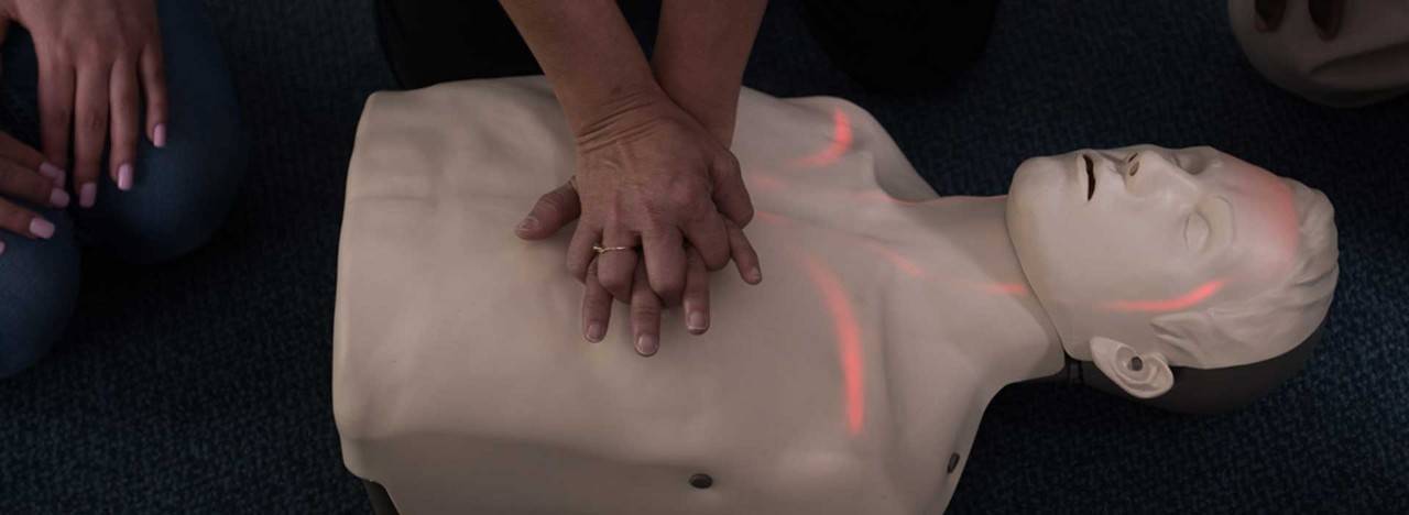 person practicing CPR on big red dummy