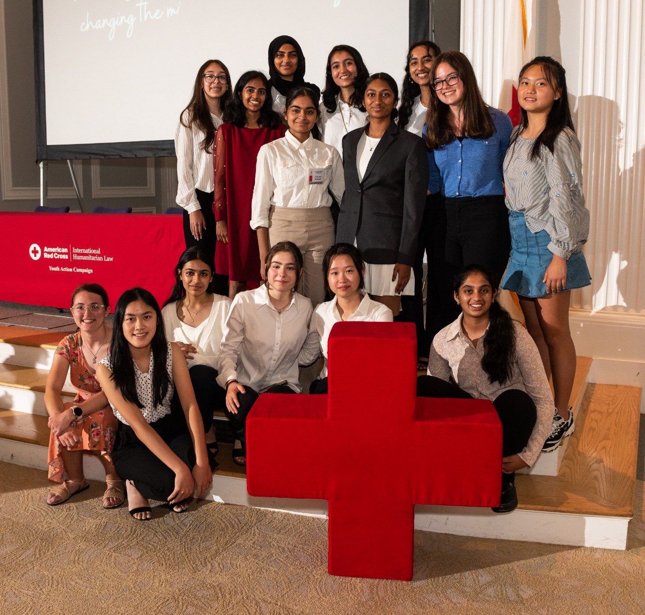 youth action campaign members posing behind a giant plush Red Cross emblem and next to an American Red Cross clothed table