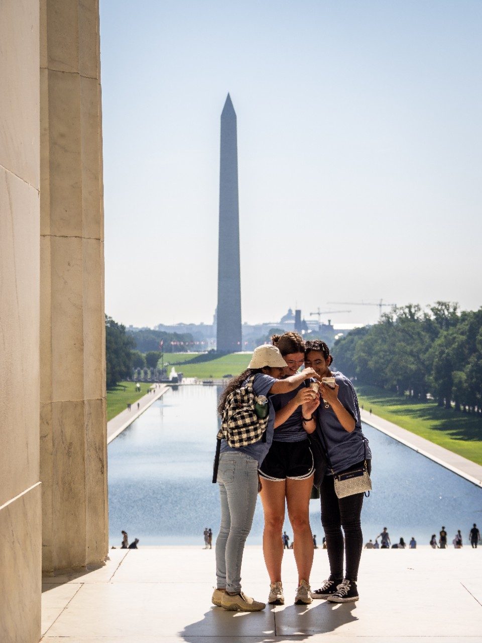 3 young people hugging with the Washington Monument in the background