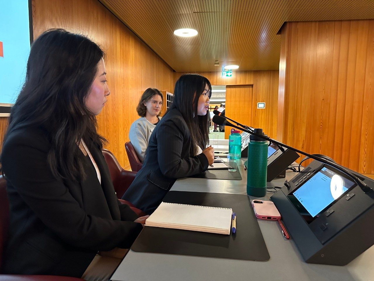 students at microphones at statutory meeting with one student speaking into a microphone