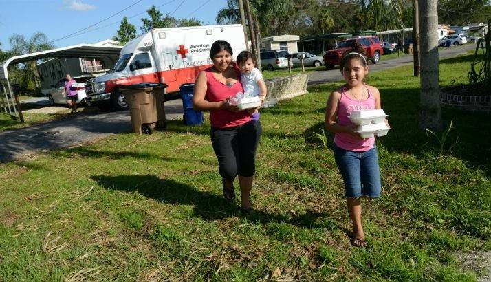 A family walks away with hot meals from the Red Cross volunteers.
