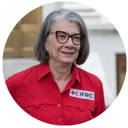 Kate Forbes wears a red shirt branded with the Red Cross and Red Crescent logo