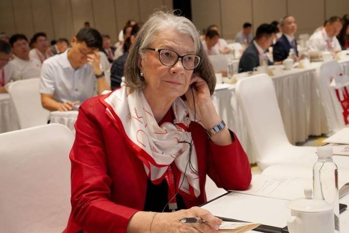 Kate Forbes sits at a desk in a meeting room.