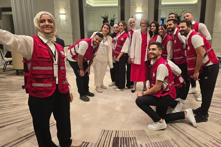 In Jordan, Kate Forbes stands with a group of young adults wearing Red Cross and Red Crescent vests.